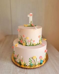 a three tiered cake decorated with flowers and the number one on it's side