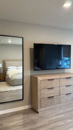 a large flat screen tv mounted to the side of a wall next to a dresser