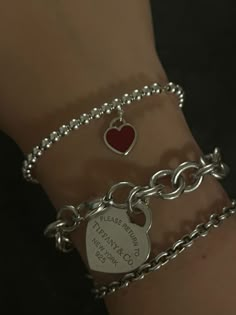 two silver bracelets with red heart charms on each one and a chain attached to the other