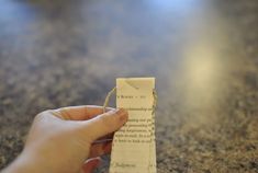 a hand holding a piece of paper with string attached to it on a counter top