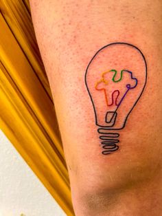 a person with a light bulb tattoo on their leg and the word love is written in multi - colored ink