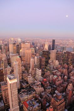 an aerial view of new york city with skyscrapers and the moon in the sky