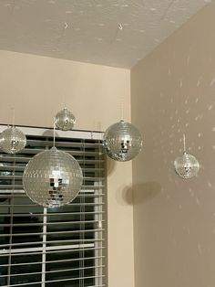 three disco ball chandeliers hanging from the ceiling in front of a window with blinds