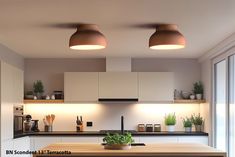 a kitchen with two lights above the counter and potted plants on the shelf next to it