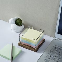 a laptop computer sitting on top of a desk next to a stack of sticky notes