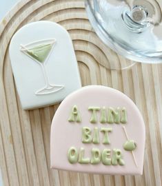 two decorated cookies sitting next to each other on a tray with wine glasses in the background