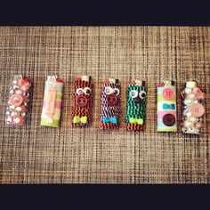 five small cell phones are lined up on a table with buttons and beads around them