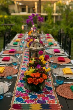 a long table is set with place settings and colorful napkins for an outdoor dinner