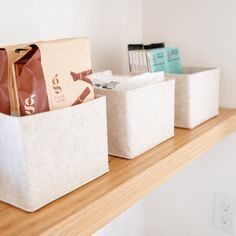 three storage bins sitting on top of a wooden shelf