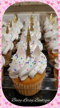 cupcakes decorated with white frosting and gold glitters are sitting on a tray