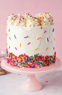 a birthday cake with sprinkles and white frosting on a pink plate