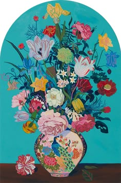 a vase filled with lots of colorful flowers on top of a wooden table next to a blue wall