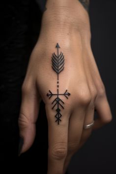 a woman's hand with an arrow tattoo on it