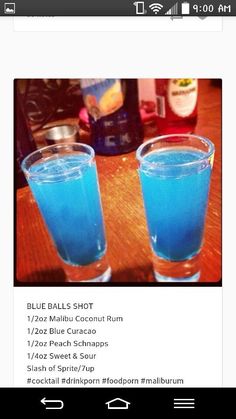 two glasses filled with blue liquid sitting on top of a wooden table