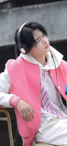 a man with headphones sitting on top of a chair wearing a pink vest and white shirt