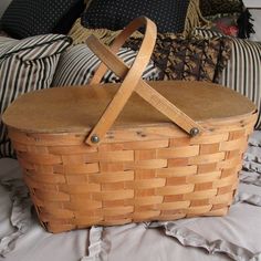 a basket sitting on top of a bed next to pillows