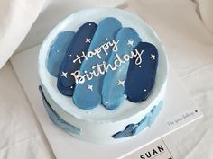 a birthday cake with blue frosting and stars on it is sitting on a table