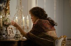 a woman sitting at a table in front of a mirror with candles and flowers on it