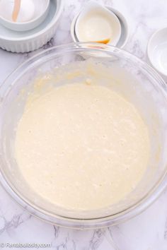 a bowl filled with batter sitting on top of a counter next to bowls and spoons