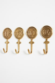 three gold coat hooks with monograms on them