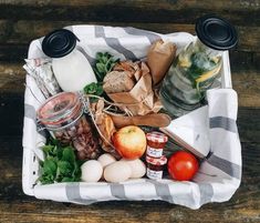 a basket filled with lots of food on top of a wooden table next to jars