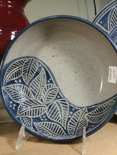 two blue and white bowls sitting on top of a wooden table next to a red vase