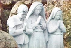 three statues of people standing next to each other in front of some rocks and grass