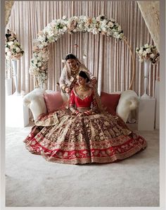 a man and woman sitting on top of a couch in front of a wedding arch