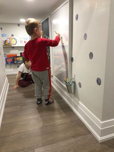 a little boy standing in front of a white wall with polka dot decals on it