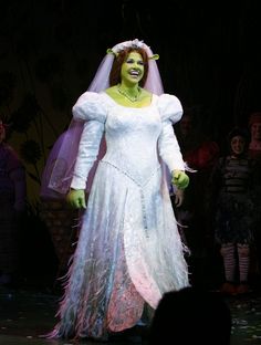 a woman in a white dress and veil on stage