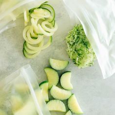 sliced cucumbers and chopped green onions on a counter top next to plastic bags