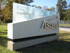 a sign for an airport that is located on the grass in front of some trees