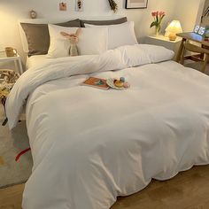 a bed with white sheets and pillows in a room