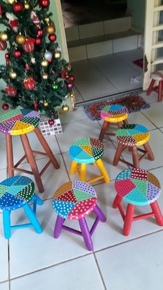 several brightly colored stools sit in front of a small christmas tree on the floor