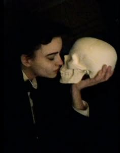 a man kissing a human skull in the dark