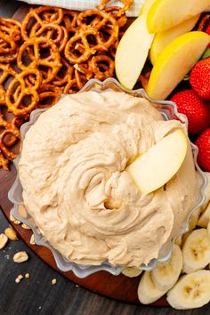 an assortment of fruit and pretzels on a wooden platter, including bananas, strawberries, apples, cinnamon rings and pretzels