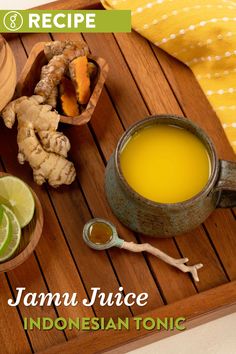 a wooden tray topped with sliced limes next to a cup of orange juice and ginger