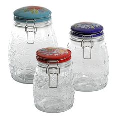 three glass jars with floral designs on the lids and one has a metal clip around the lid