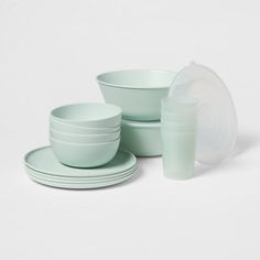 a set of green dishes and cups on a white surface with one empty cup in the middle