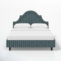 an upholstered bed with white pillows and blue pinstripe fabric headboard