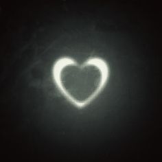 a heart shaped object in the dark with white dots on it's side and black background