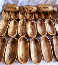 a bunch of wooden plates sitting on top of a white cloth covered tablecloth,