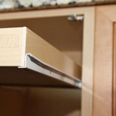 a close up view of the bottom drawer of a kitchen cabinet with wooden doors and drawers