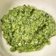 a white bowl filled with green food on top of a table