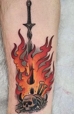 a man's leg with a tattoo on it that has flames and skulls around it