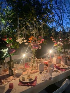 a table set for dinner with candles and flowers in the center is lit by candlelight