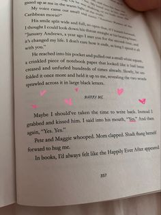 someone is reading a book with pink hearts on the pages and writing in black ink