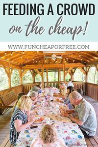 a group of people sitting at a long table eating food in a covered pavilion with lights strung from the ceiling