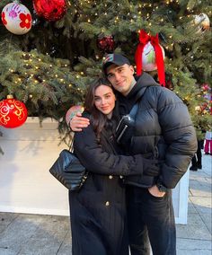 a man and woman standing in front of a christmas tree