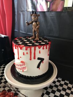 a birthday cake with a teddy bear on top and the number seven painted on it